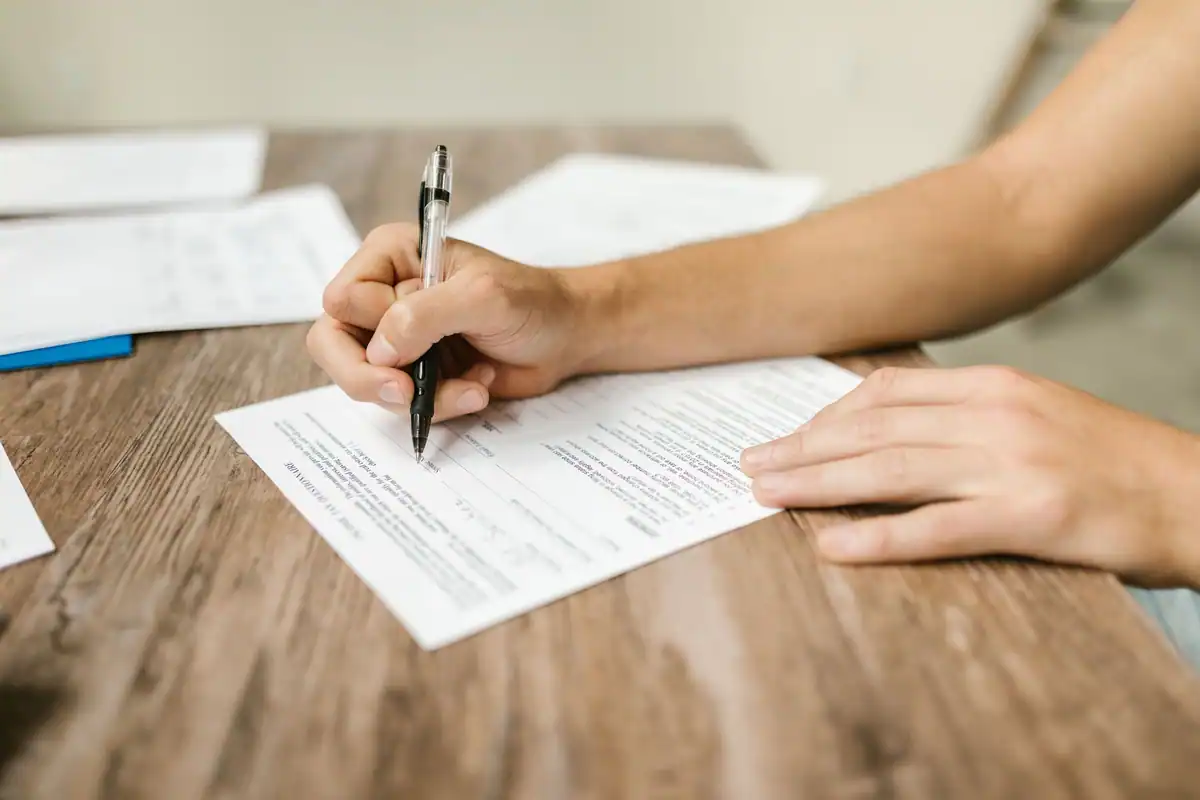 Mână care completează cu pixul o declarație privind acceptarea moștenirii