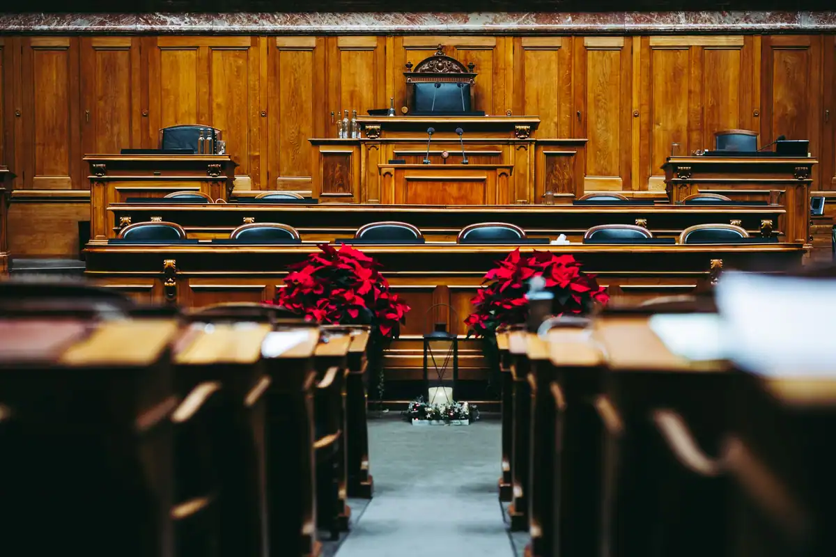 Sală de judecată spațioasă din lemn, cu băncile goale înaintea ședinței