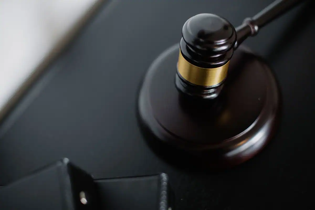 Ciocănel de judecător din lemn lângă dosare pe masa din sala de judecată