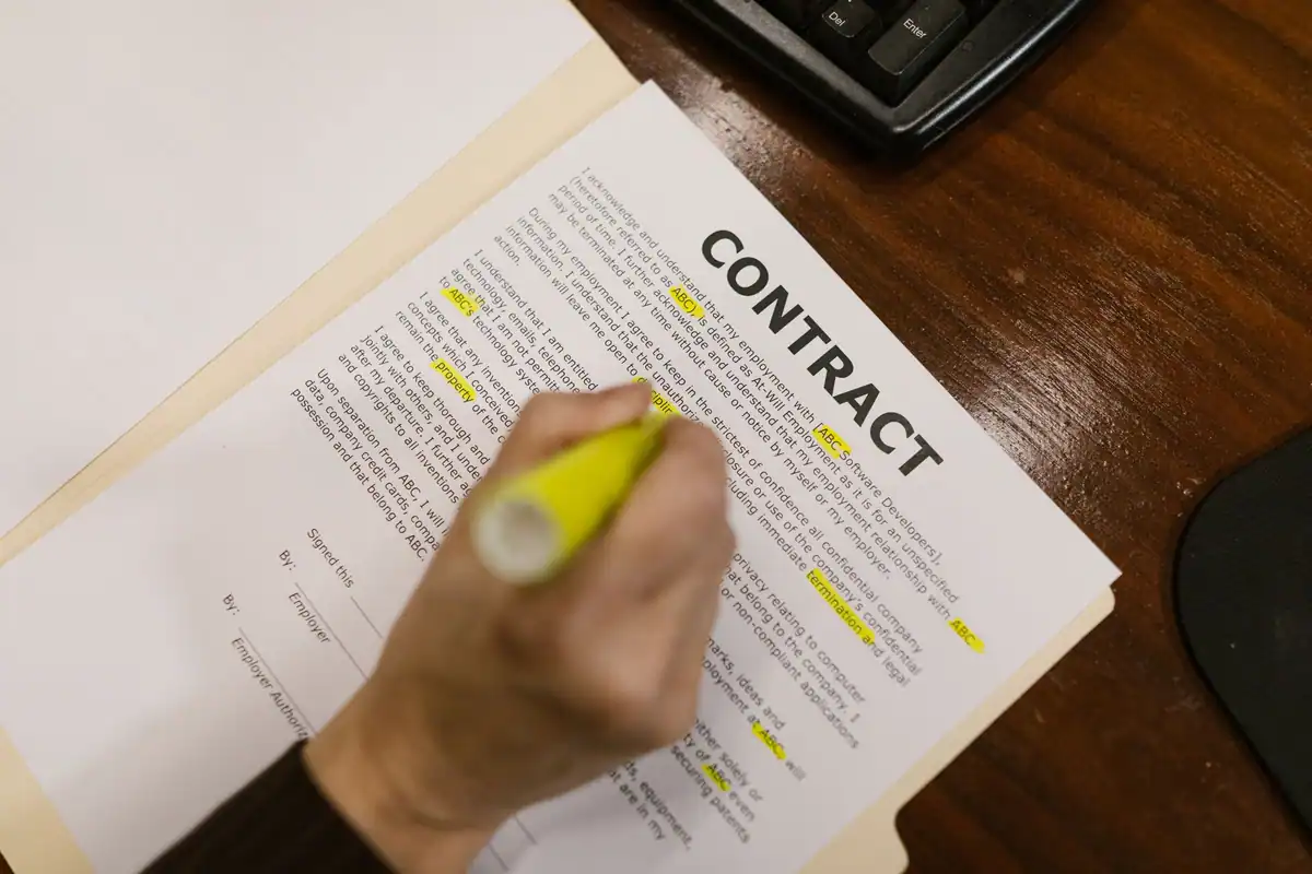 Persoană care subliniază cu markerul clauzele dintr-un contract pe birou din lemn