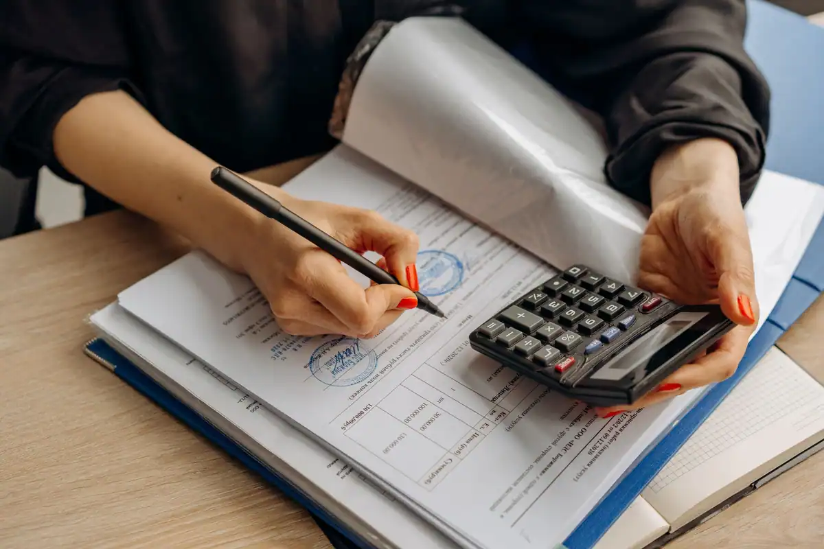 Persoană care calculează sumele cu un calculator și semnează actele contractului
