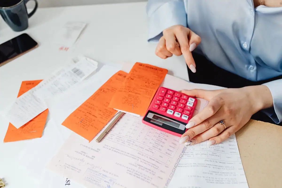 Femeie care calculează cheltuielile cu chitanțe și calculator la birou