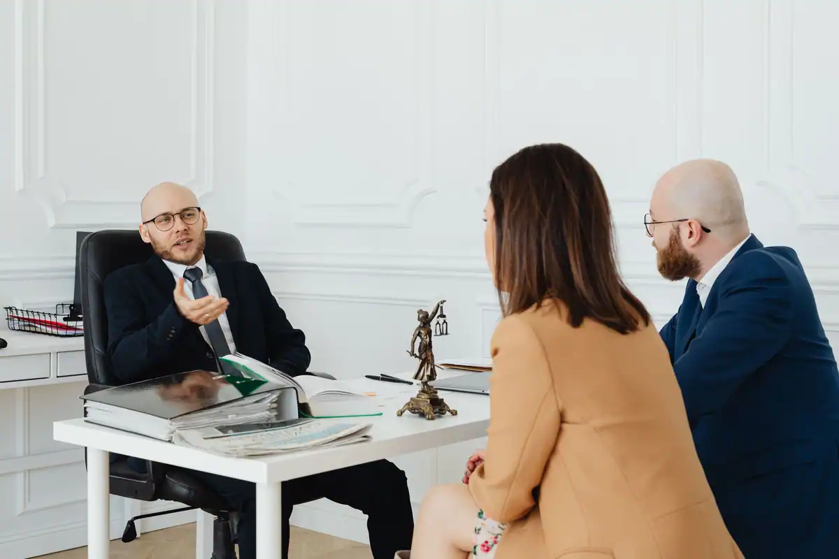 Trei adulți într-o întâlnire formală care discută onorariul și serviciile juridice