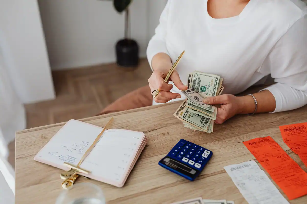 Femeie care calculează cheltuielile copilului cu calculator, bani și chitanțe