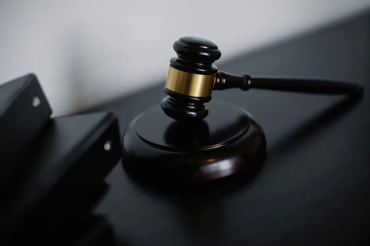Ciocănel de judecător lucios, cu detalii aurii, lângă dosarele cauzei