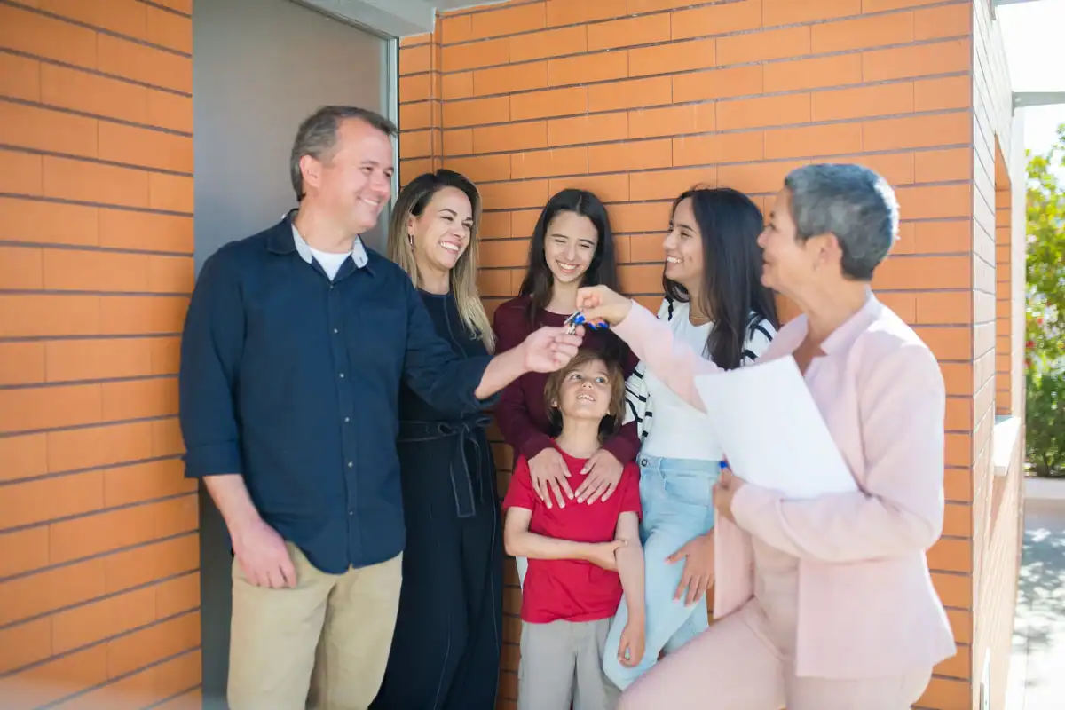 Familie bucuroasă care primește cheile unei case donate de părinți