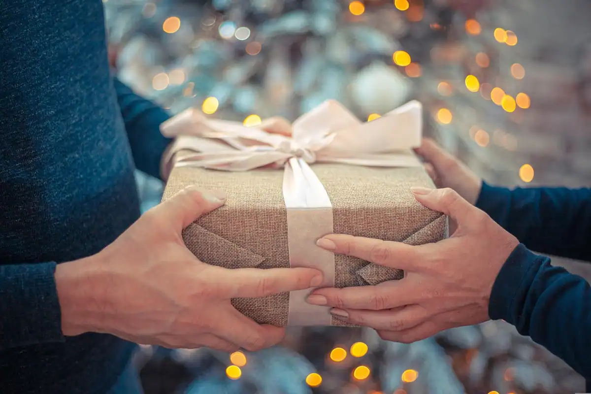 Cutie de cadou cu panglică ținută în mâini, simbol al darurilor făcute în familie